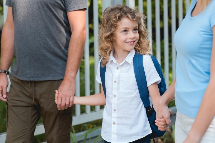 girl walking with parents to school