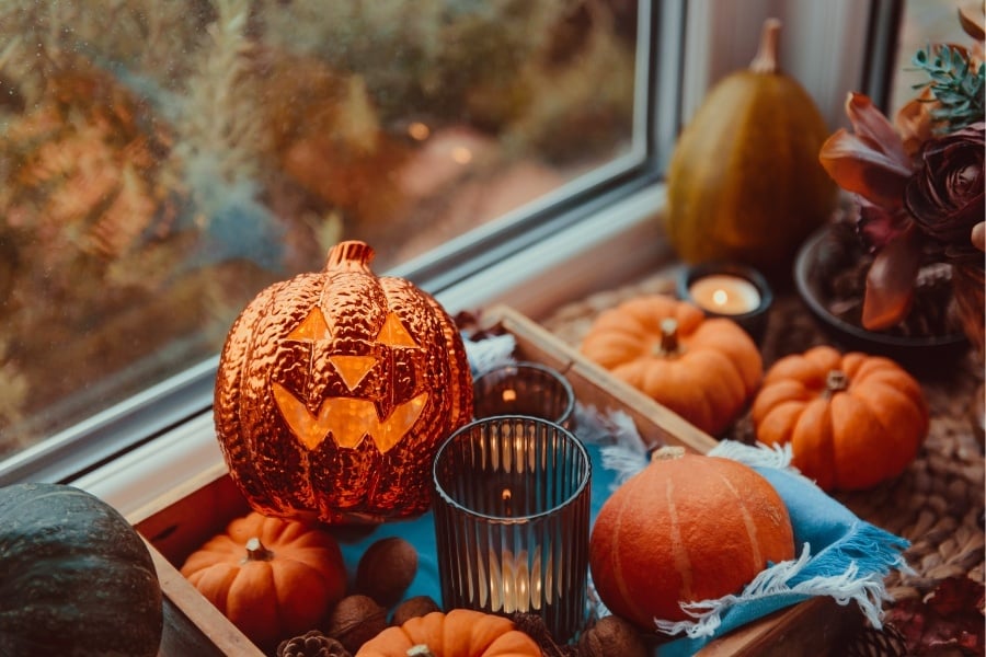 jack o lantern candle, pumpkins, tray, and fall decor on windowsill