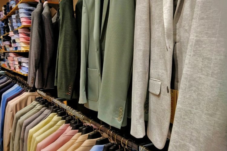elegant suit jackets and shirts hung up neatly on shelves and rack in store