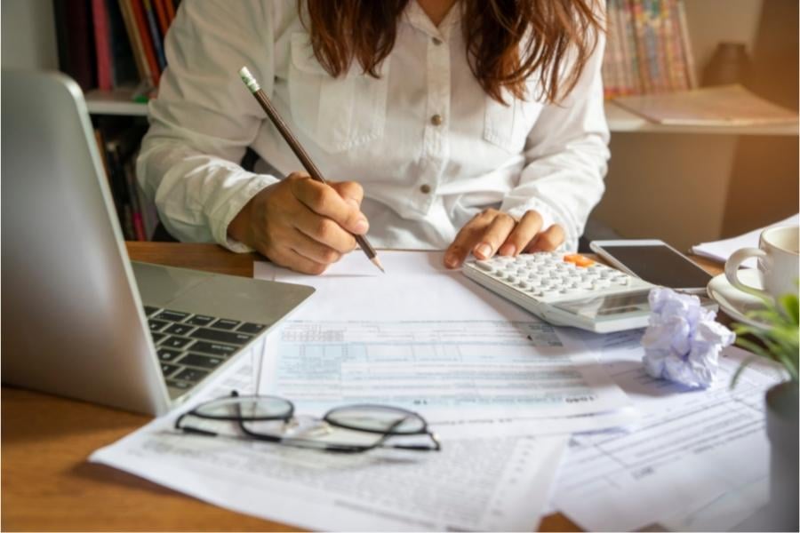 woman with papers, laptop, calculator