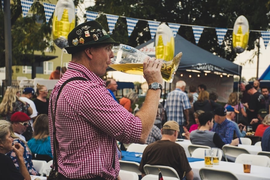 Man drinking beer from glass stein in German folk clothing