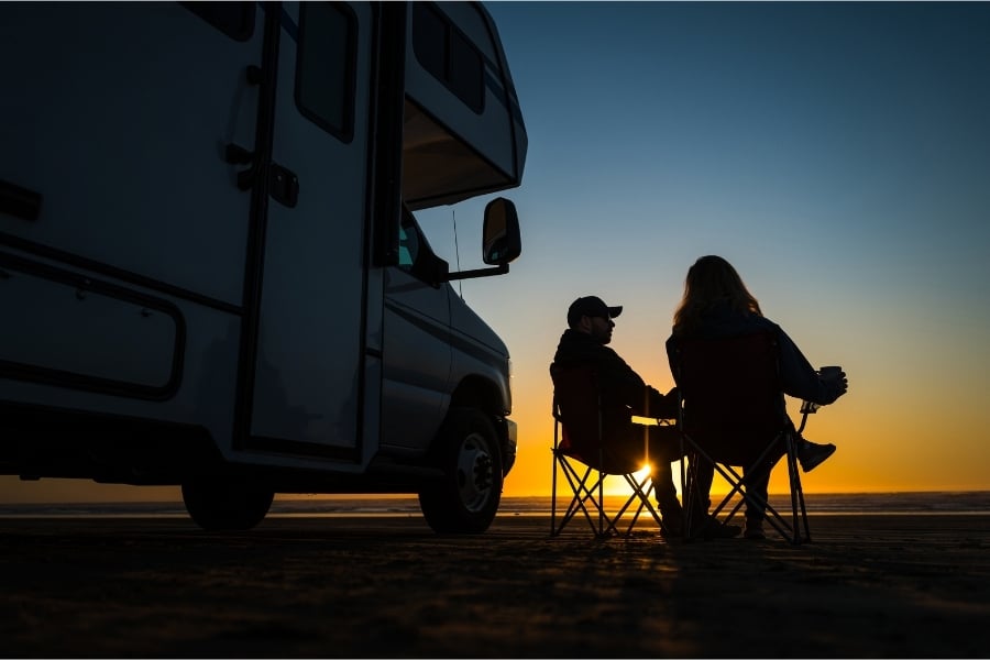 couple relaxing on beach by RV