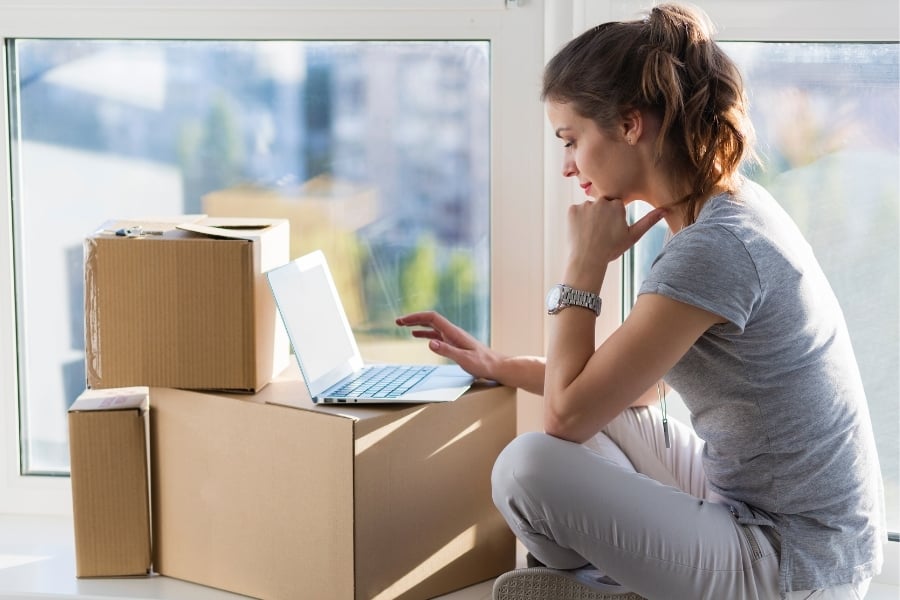 woman with laptop and moving boxes 