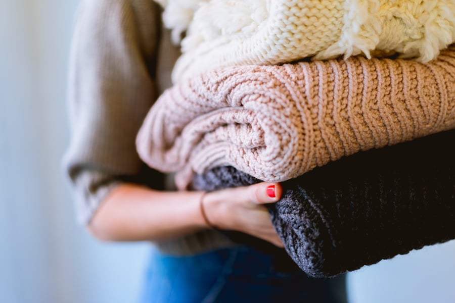 woman carrying folded sweaters