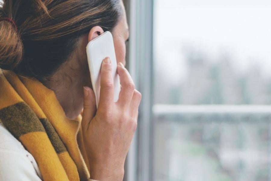 woman talking on phone while looking out window