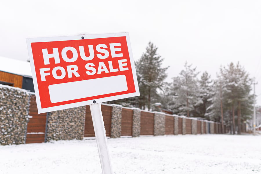 house for sale sign in snowy yard