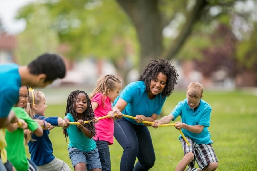 adults and children playing tug of war