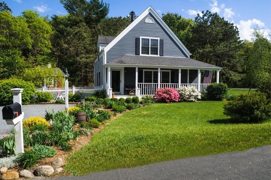 grey home with flowerbeds and green lawn