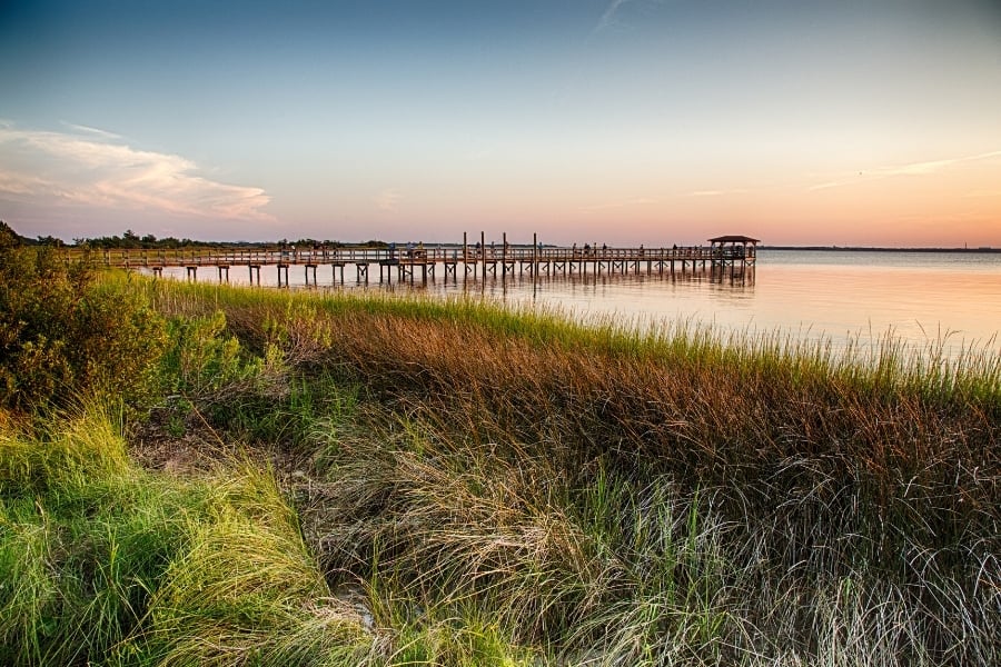 Cape Fear River in North Carolina, pier with grass on shoreline, ocean, and skyline