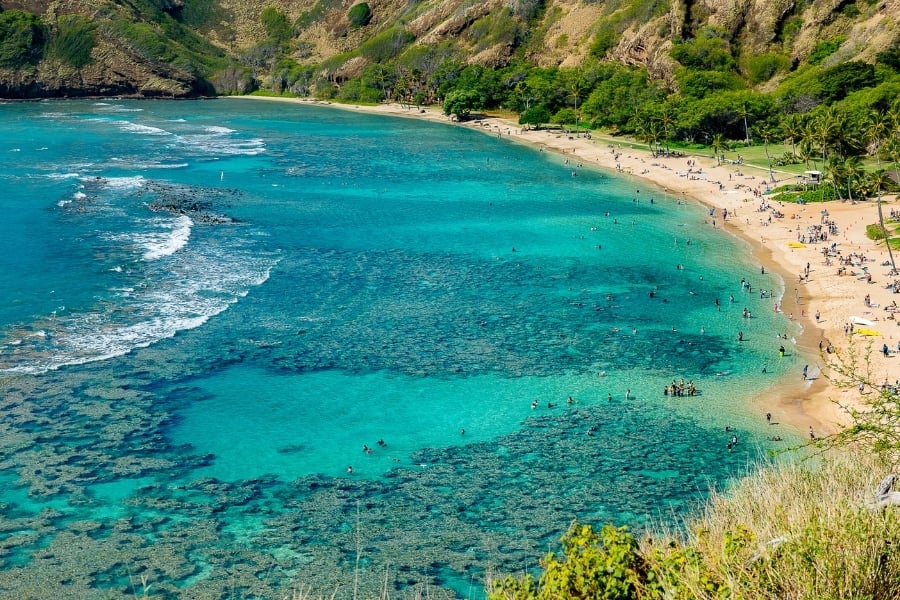 turquoise ocean water, sandy beach, people laying on beach inHanauma Bay on the island of Oahu, Hawaii