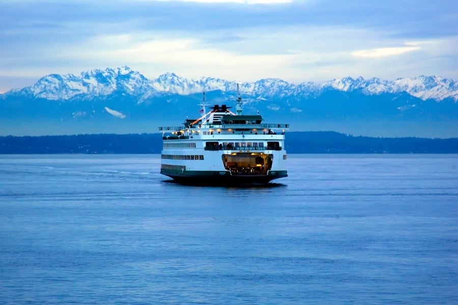 Seattle-Bremerton Ferry at dusk on calm water in Washington state with snowcovered mountains in distance