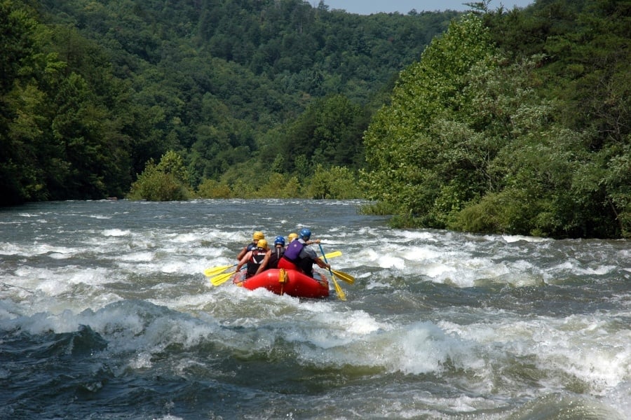Group of people white-water rafting down river. 