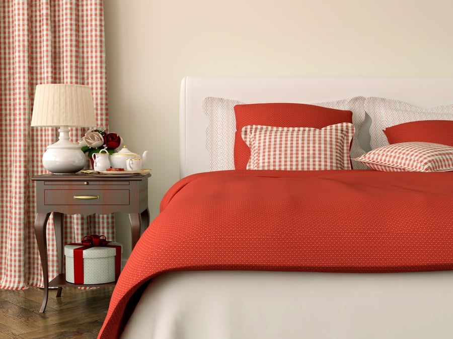 Bed with red bedding and lamp on table