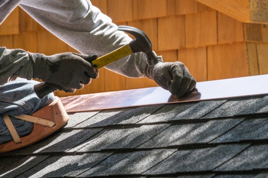 person repairing roof with hammer