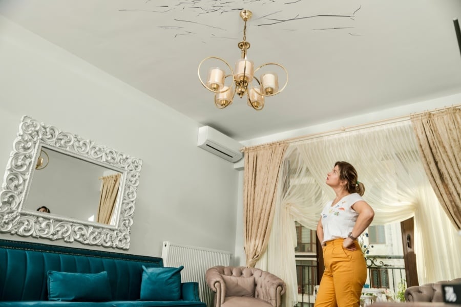 woman looking at cracks in ceiling