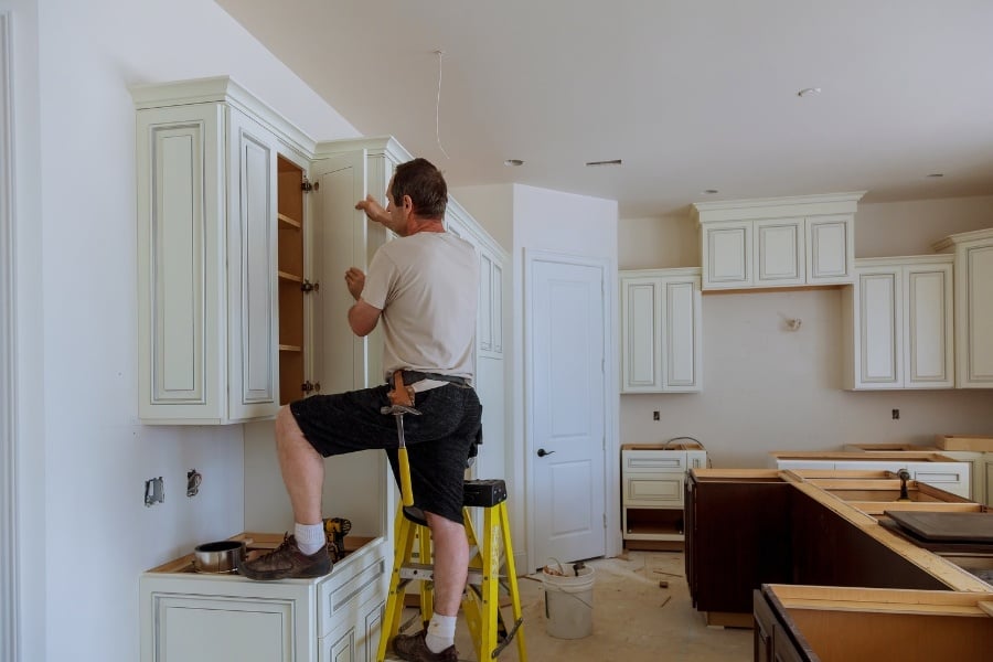 man installing new cabinet in kitchen