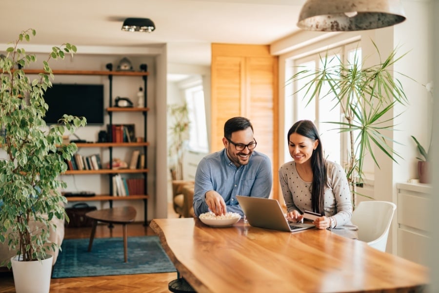 couple looking at finances on a laptop, kitchen table, woman holding credit card