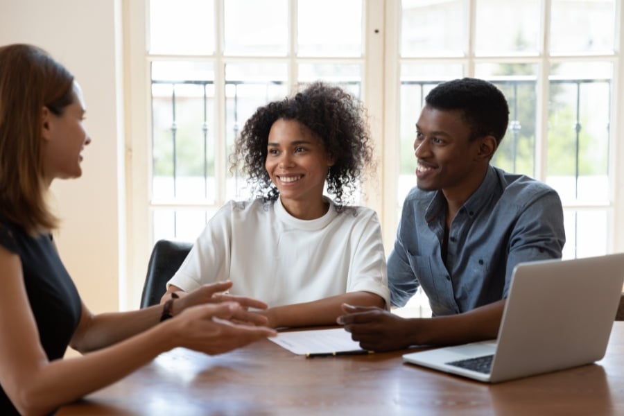 Man and woman meet with female real estate agent with laptop. 