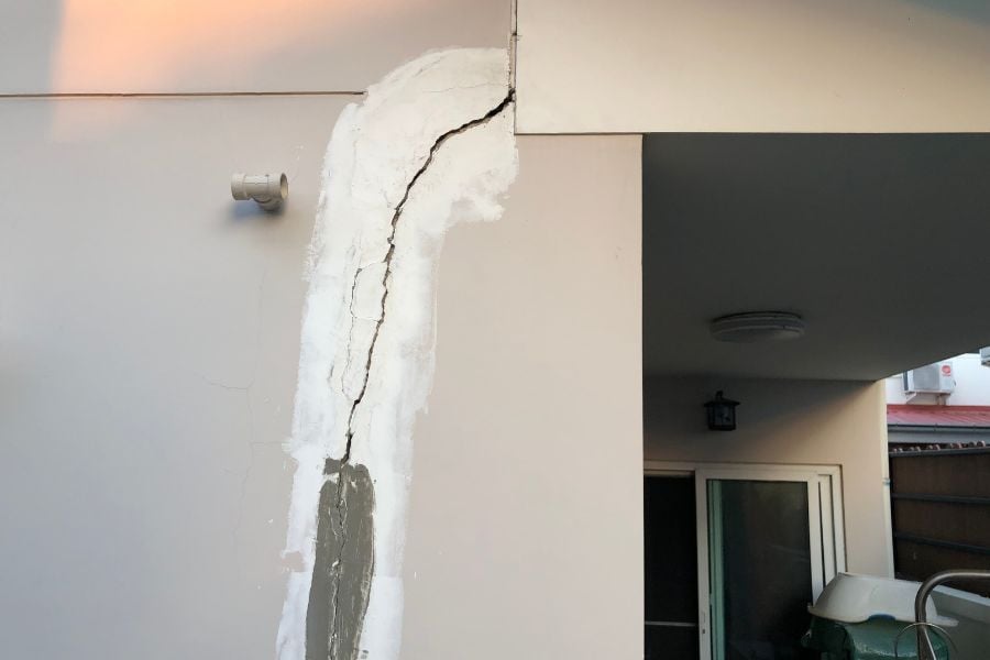 Home with crack in wall with view of back patio door and fence in the back.