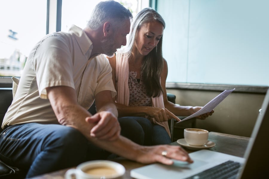 couple looking at paperwork and laptop with table and cups of coffee