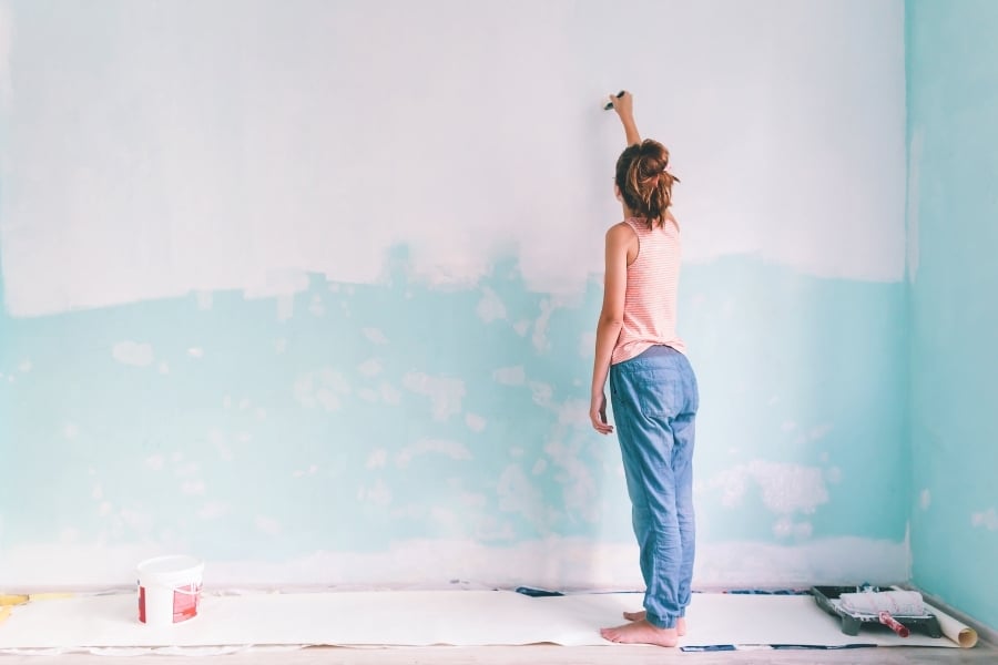 Woman wearing pink and blue painting turquoise wall white. 
