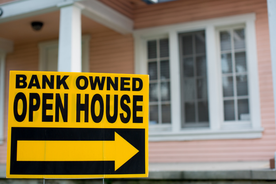 pink home with yellow sign which states bank owned open house