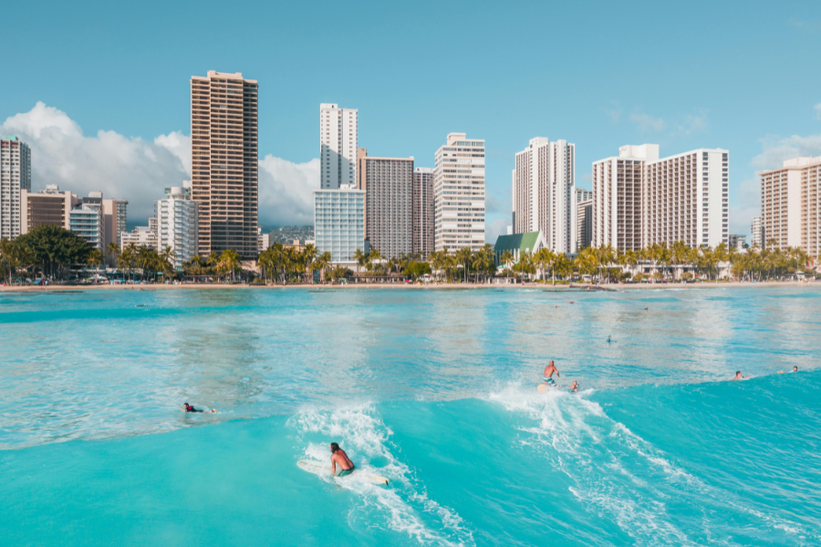 View behind surfers catching a wave at Waikiki Beach, Oahu Hawaii 
