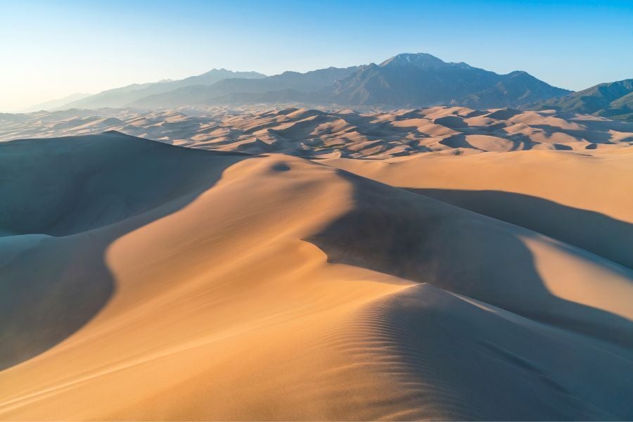View of silky sand dunes in Great Sand Dune National Park in Colorado with mountains behind.