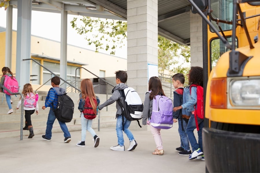 chilcren leaving school bus in front of school