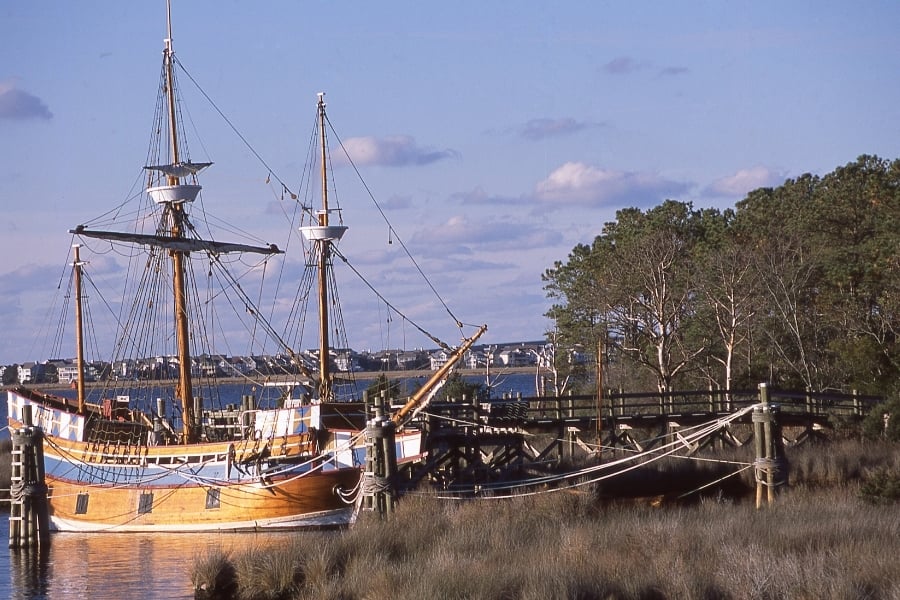Restored ancient ship the Susan Constant at dock in Jamestown Settlement Williamsburg Virginia, colonial build wooden ship with masts and cables in water next to shore with grass and dock