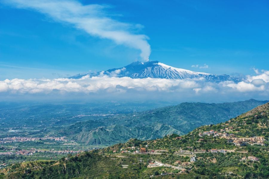 View of Mount Etna and clouds and blue sky with towns below in Sicily