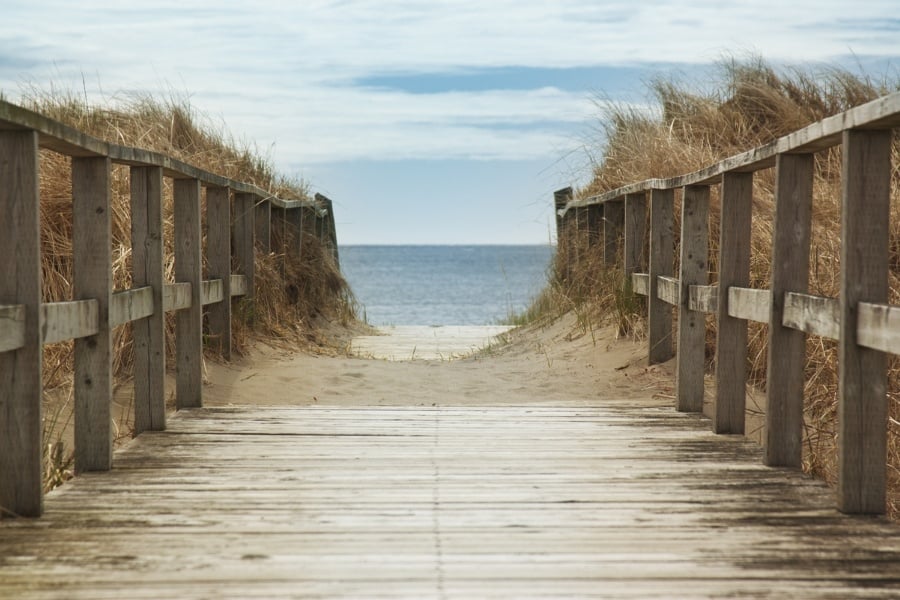 Boardwalk leading to sandy beach and water ahead.