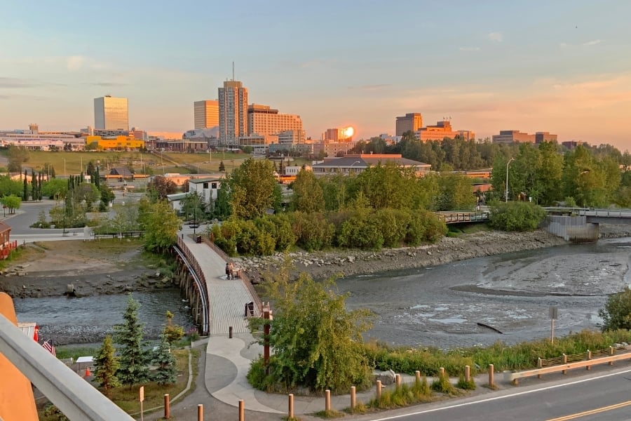 Sun setting over Anchorage, Alaska with view of river and path leading over bridge 