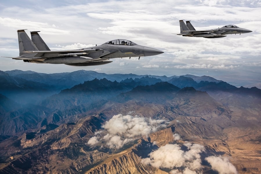 F-15 Eagle fighter jets flying over mountainous terrain.  