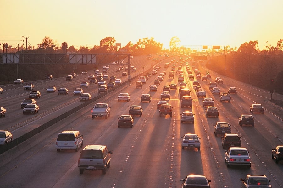 cars in traffic on multilaned highway with sun setting