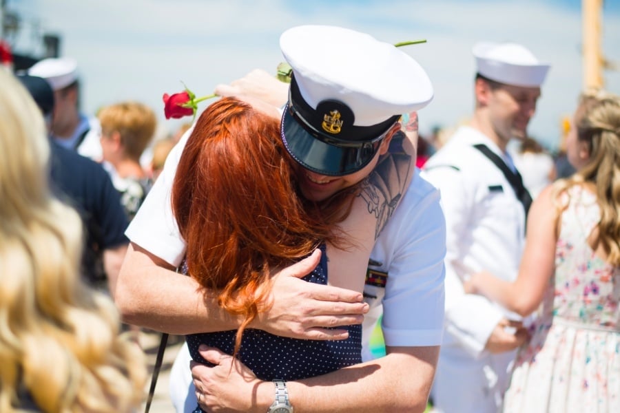 woman hugging husband in navy dress uniform after deployment