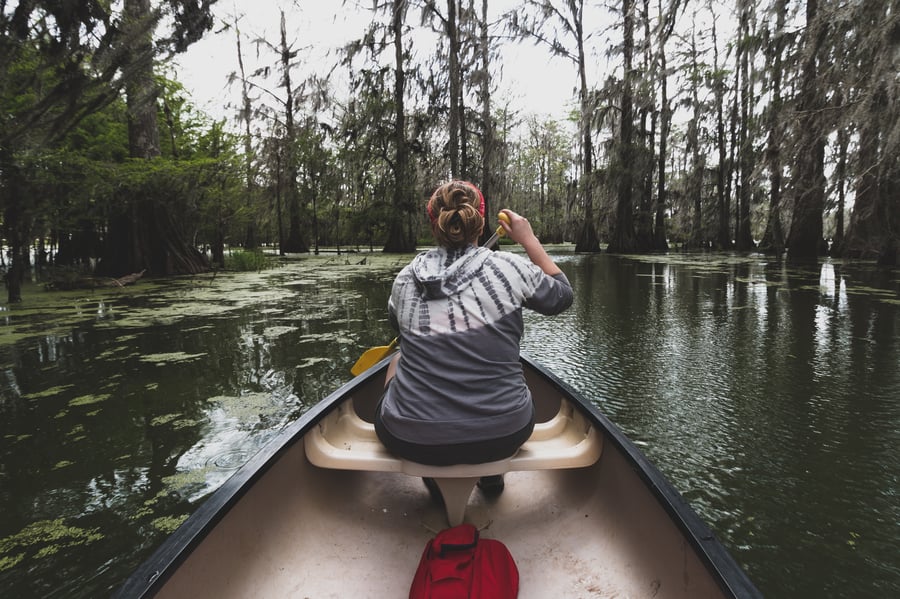 Woman paddling a canoe down a river. 