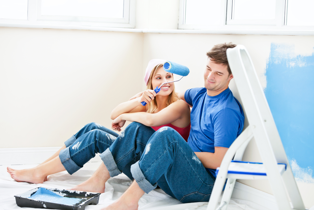 Charming couple relaxing after painting a room in their new house