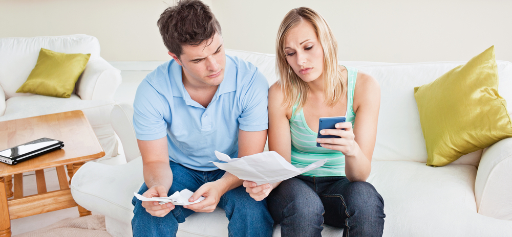 Concentrated young couple calculating bills sitting on the sofa in the living-room