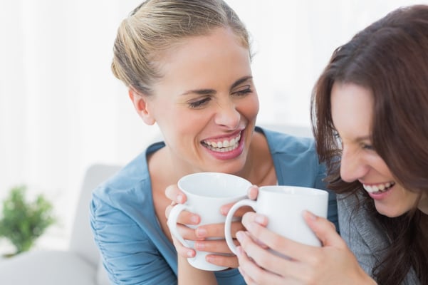 Friends bursting out laughing while having coffee sitting on the sofa.jpeg