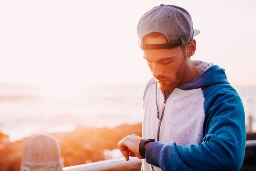 Man with hat checks smart watch. 