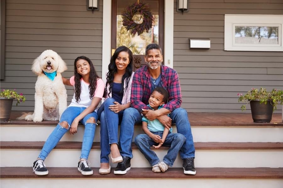 family sitting on front porch steps of rental home