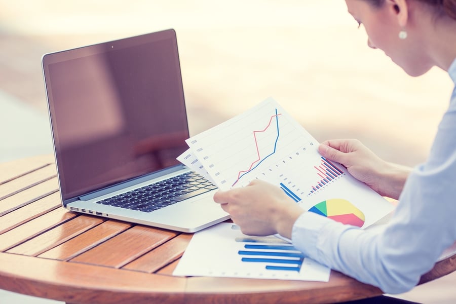 woman looking at paperwork and laptop 