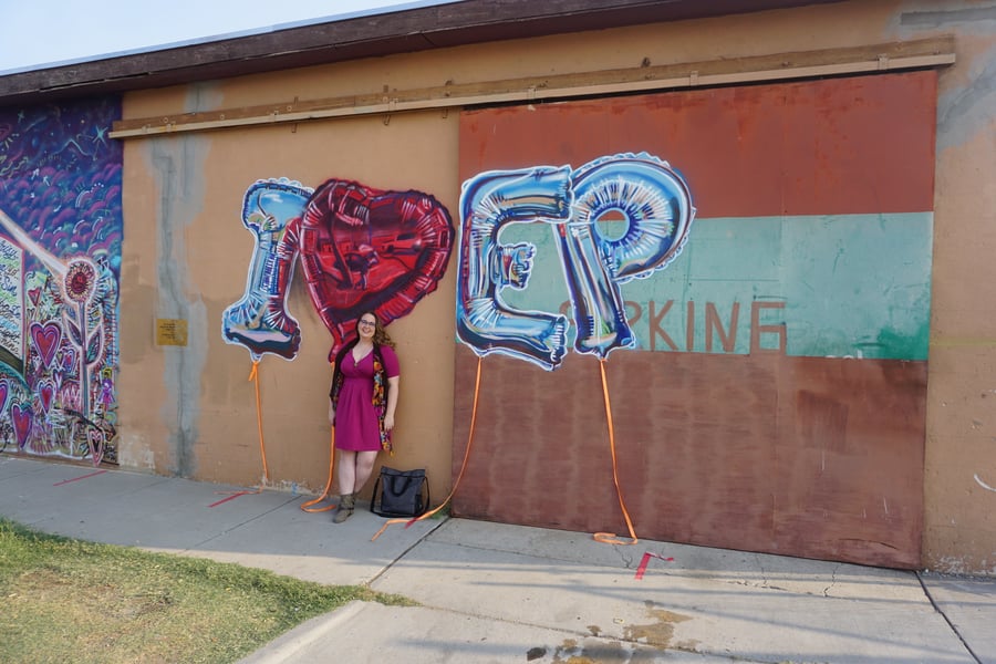 Photo of woman in pink dress standing in front of an I Love EP mural at Old Sheepdog Brewery in El Paso, Texas by Fort Bliss 