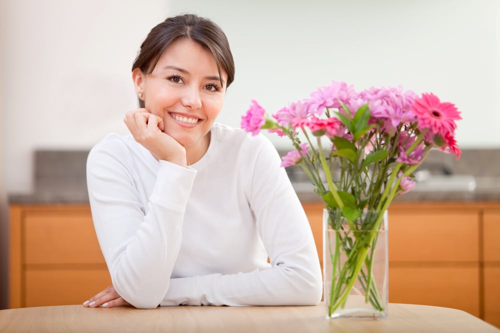  woman next to a bunch of  flowers and smiling - indoors