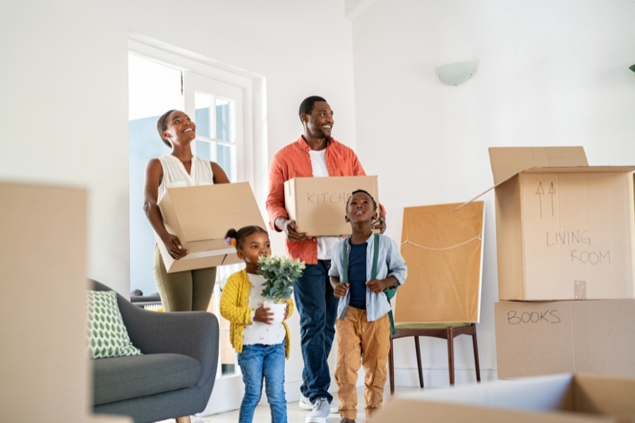 parents and two children carrying boxes into home