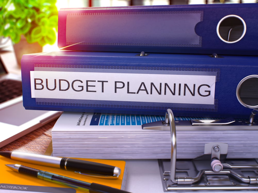 Blue Ring Binder with Inscription Budget Planning on Background of Working Table with Office Supplies and Laptop. Budget Planning Business Concept on Blurred Background. 3D Render.