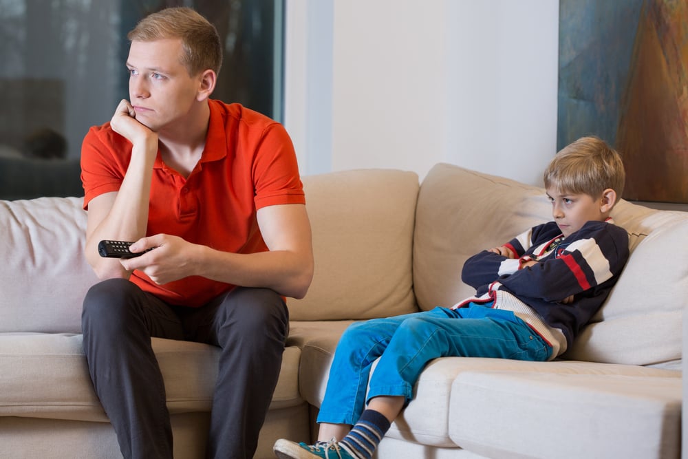 Bored child and father is watching TV at home