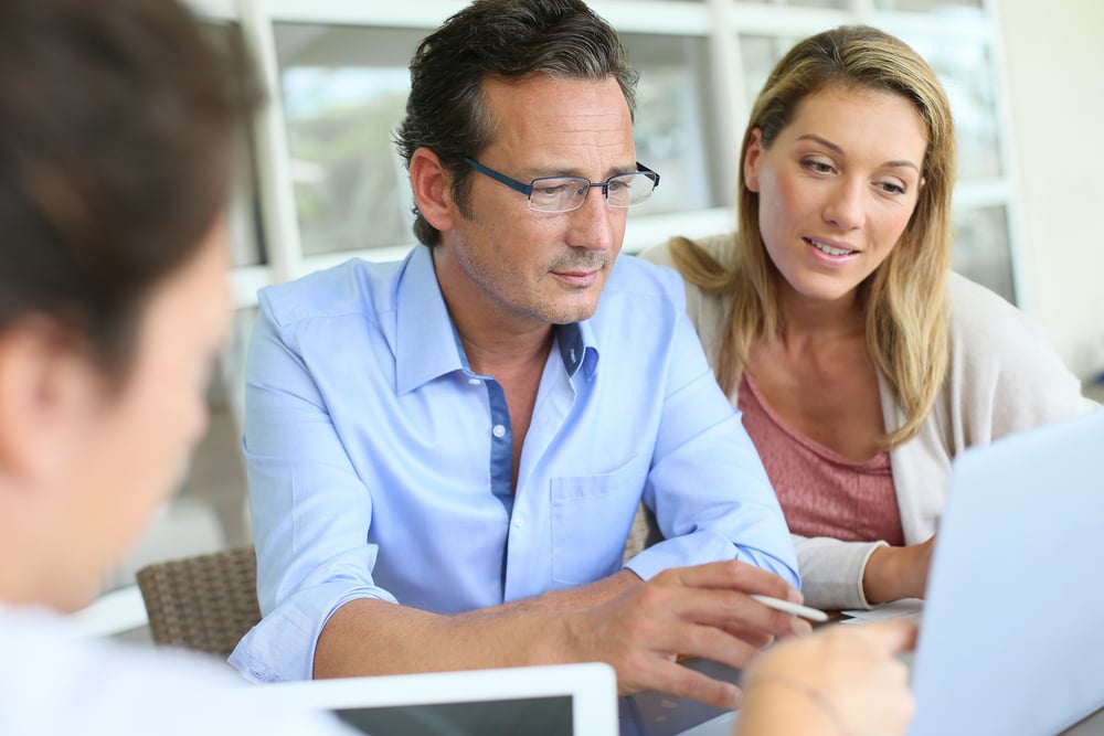 Couple signing home closing documents on digital table