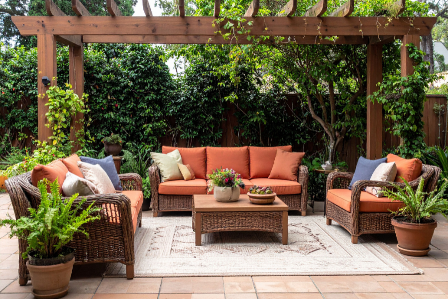 Backyard patio with lush greenery and orange patio furniture.